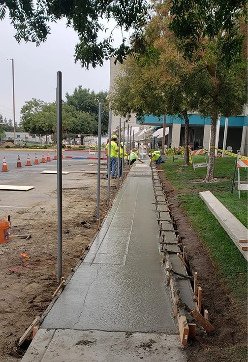 A sidewalk being built in the middle of an urban area.