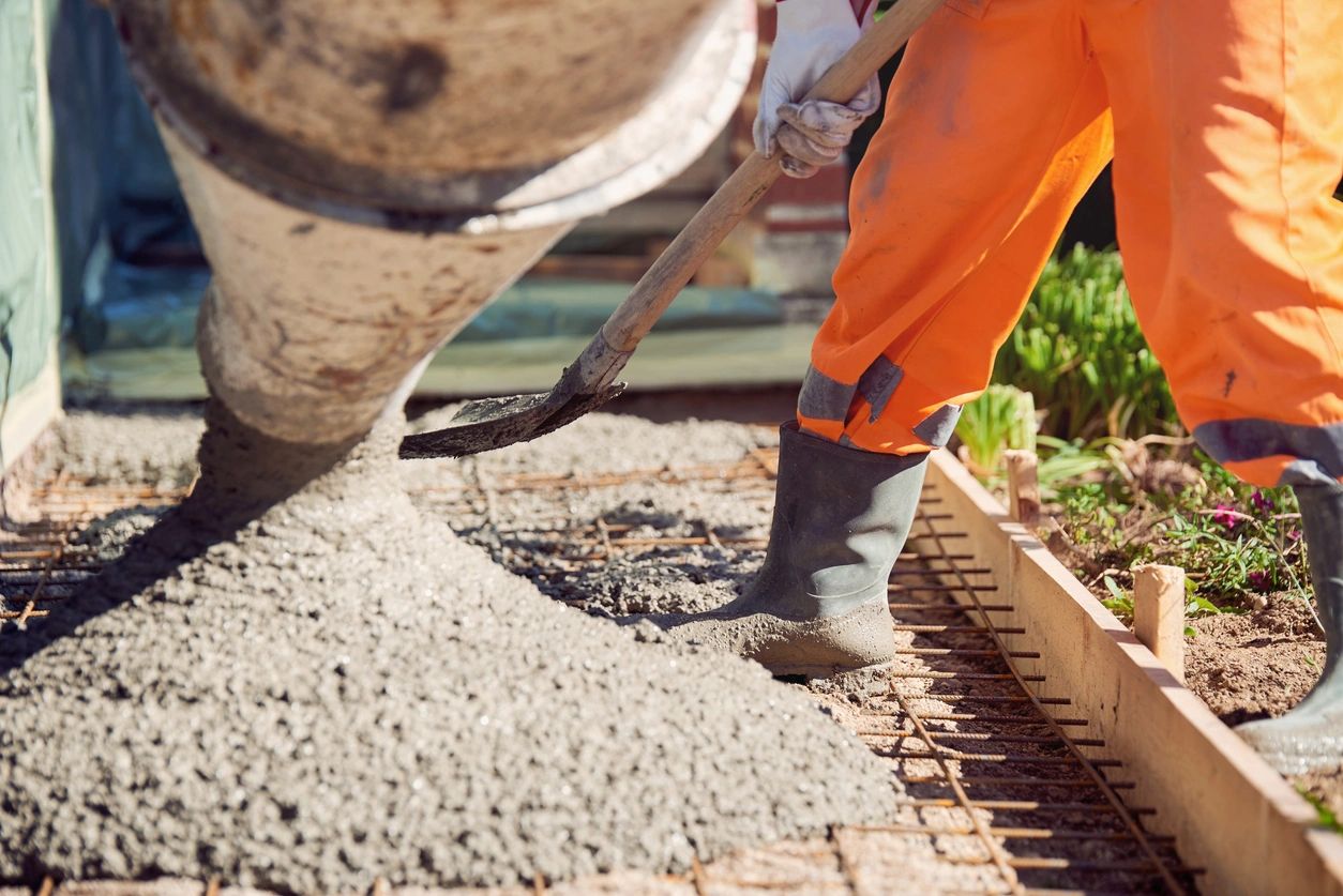 A person in orange pants and boots working on concrete.